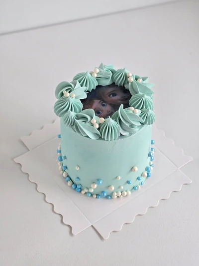 Light blue buttercream cake with a baby edible image topper and pearl details