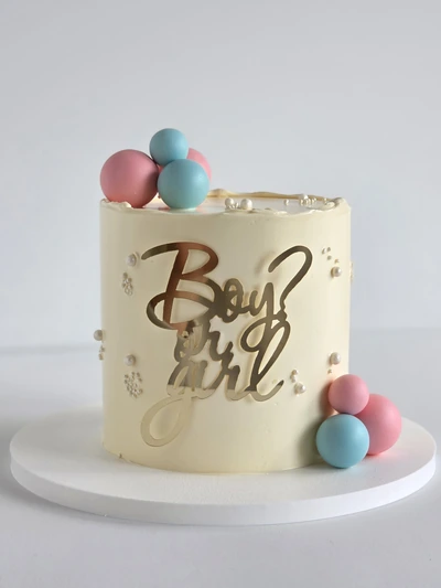 Gender reveal cake with pastel balloons and Boy or Girl topper